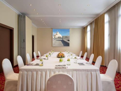 a conference room with a long table with white chairs at Treffen House Doha - Souq Waqif and next to Msheireb Metro Station in Doha
