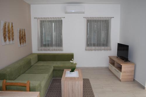 sala de estar con sofá verde y TV en Villa Mio Mare en Cres