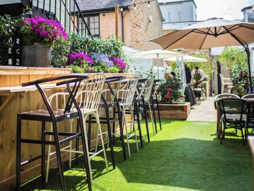 a row of chairs and tables with umbrellas in a garden at Castle Hotel Windsor in Windsor