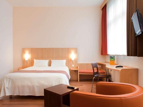 um quarto de hotel com uma cama, uma secretária e uma cadeira em ibis Karlsruhe Hauptbahnhof em Karlsruhe