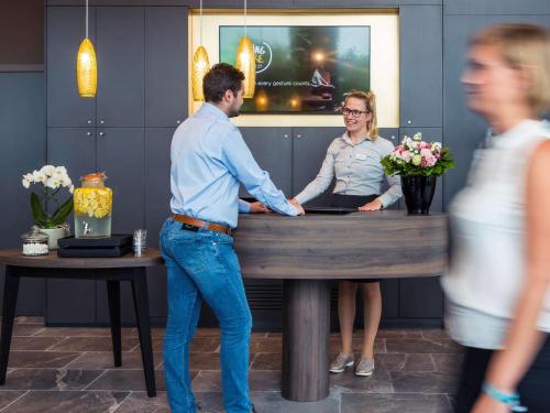 een man en een vrouw die aan een balie staan bij Mercure Blankenberge in Blankenberge