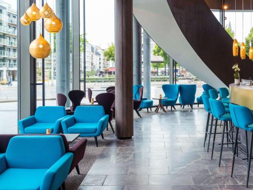 a lobby with blue chairs and a bar at Mercure Blankenberge in Blankenberge