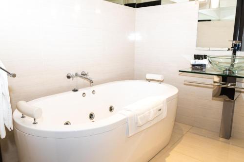 a white bath tub in a bathroom with a sink at Freddy's Boutique Villas in Warrnambool