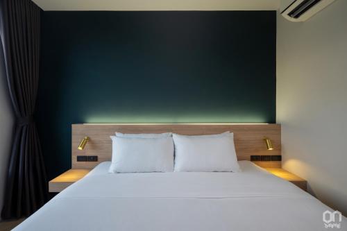 a bedroom with a large white bed with a green wall at ON Thapae Gate Chiangmai in Chiang Mai