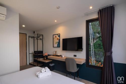 1 dormitorio con escritorio, TV y ventana en ON Thapae Chiangmai en Chiang Mai