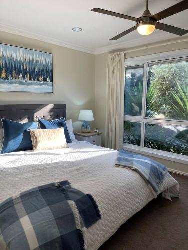 a bedroom with a bed with a ceiling fan and a window at Coastal Country Retreat, Spa, fireplace, pet friendly, FREE WIFI wine & chocolates, Kilarney, 10 minutes to Phillip Island in Kilcunda