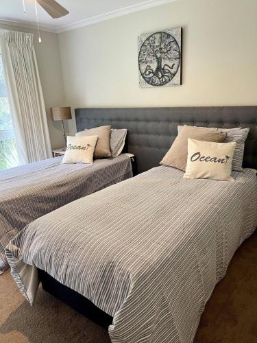 a bedroom with two beds and a clock on the wall at Coastal Country Retreat, Spa, fireplace, pet friendly, FREE WIFI wine & chocolates, Kilarney, 10 minutes to Phillip Island in Kilcunda