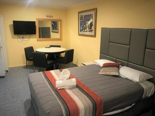 a bedroom with a bed and a table with chairs at Toukley Motor Inn in Toukley