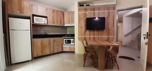 cocina con mesa y TV en la pared en Betara2, en Florianópolis