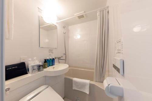 a white bathroom with a toilet and a sink at JRクレメントイン今治 in Imabari