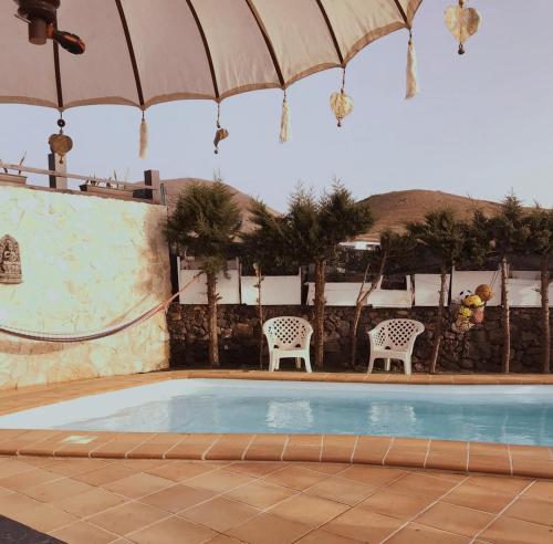 een zwembad met twee stoelen en een parasol bij Lanzate in Tinajo