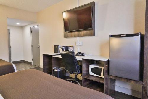a hotel room with a desk and a tv on the wall at Baymont by Wyndham Medicine Hat in Medicine Hat