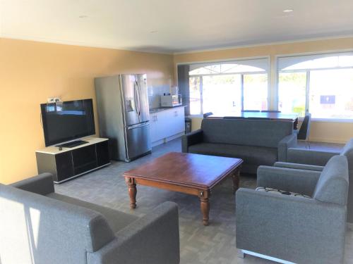 a living room with couches and a tv and a table at Toukley Motor Inn in Toukley