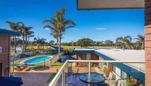 a balcony with a view of a pool and palm trees at Surfside Merimbula Holiday Apartments in Merimbula