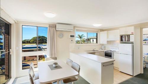 a kitchen with a table and chairs and a kitchen with a view at Surfside Merimbula Holiday Apartments in Merimbula