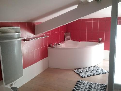 y baño con bañera y azulejos rojos. en La Salamandre, en Le Busseau