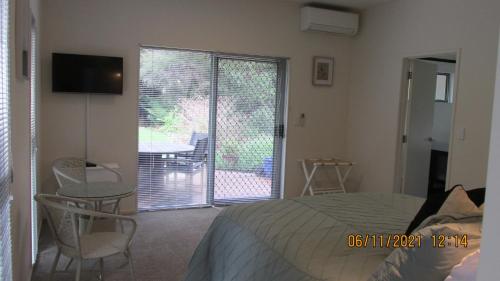 a bedroom with a bed and a sliding glass door at Fantail River Lodge in Haruru
