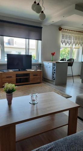 un salon avec une télévision et une table dans l'établissement Riverside Apartment Pärnu, à Pärnu