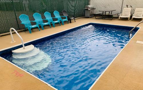 a swimming pool with blue chairs and a table at Franklin Terrace Motel in Seaside Heights