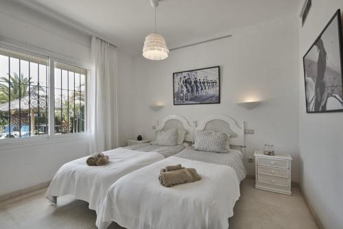 a white bedroom with two beds with towels on them at Villa Pinsapo in Estepona