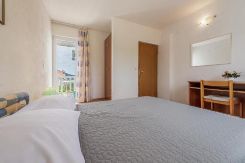 a bedroom with a bed and a desk and a window at Olive gardens in Primošten