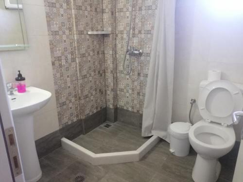 a bathroom with a shower with a toilet and a sink at Sagma Central Rooms in Perissa