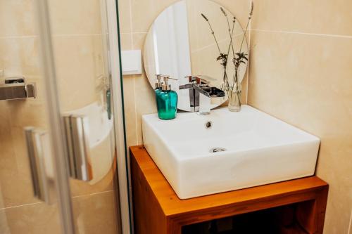 W łazience znajduje się biała umywalka i lustro. w obiekcie Cabanas da Colina w mieście Bombarral