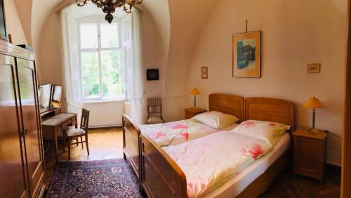 a bedroom with a bed and a desk and a window at Ferienwohnung Schloss Schrattenthal in Schrattenthal