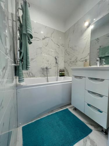 ein Badezimmer mit einer weißen Badewanne und einem grünen Teppich in der Unterkunft My Kingdom in Gulbene