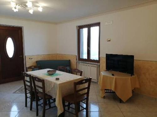 a dining room with a table with chairs and a television at B&B Oliva in Scala