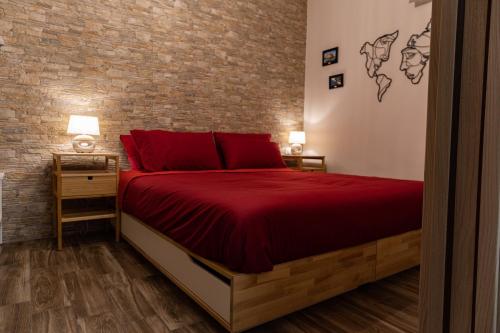 a bedroom with a red bed and a brick wall at Tizzy Apartment & Rooms in Bari