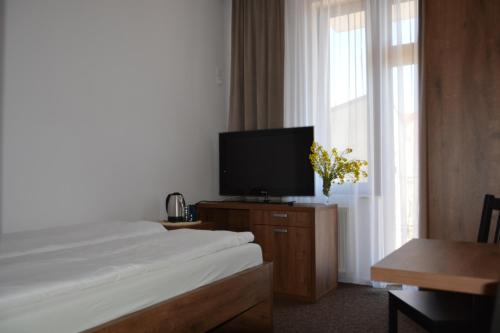 a hotel room with a bed and a flat screen tv at WILLA ELITA in Krynica Morska