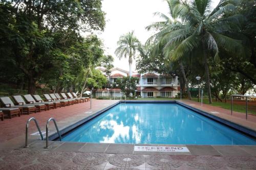 a swimming pool with chairs and a house in the background at The Gateway Hotel Pasumalai Madurai in Madurai
