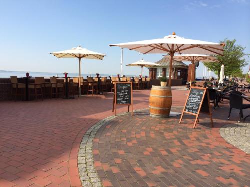 a patio with umbrellas and tables and chairs at Strand-Hotel Seenelke in Wilhelmshaven