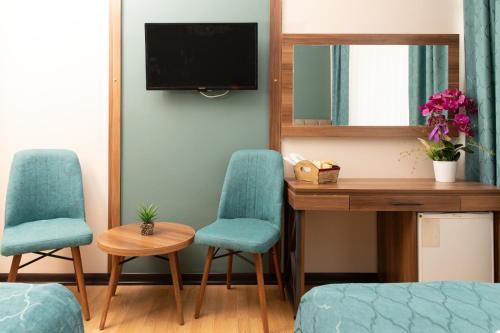 a room with two chairs and a desk and a television at Buldum Otel in Ankara