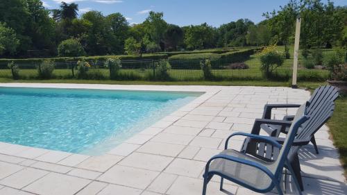 duas cadeiras sentadas ao lado de uma piscina em La Roseraie em Neuville-du-Poitou