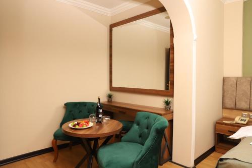 a room with two green chairs and a table and a mirror at Buldum Otel in Ankara