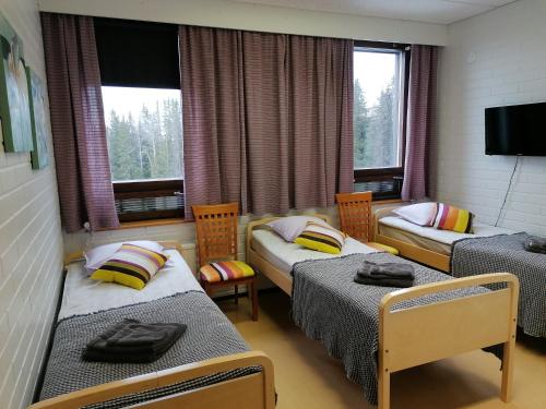 a room with two beds and two chairs and windows at Kaidanojan Kartano in Uusikartano