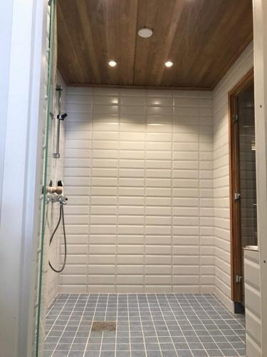 a shower in a bathroom with a tiled wall at Haikolan talo in Lipinlahti