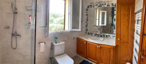 Un baño con inodoro, lavabo y espejo. en Villa Quatre Vents, en Punta Prima