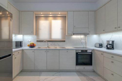 a white kitchen with white cabinets and a sink at Manuel's Dream in Ádhele