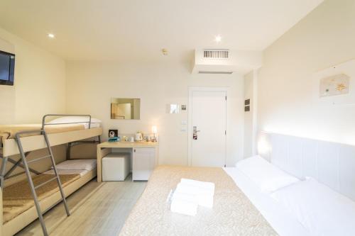 a small room with two bunk beds and a desk at Ferretti Beach Hotel in Rimini