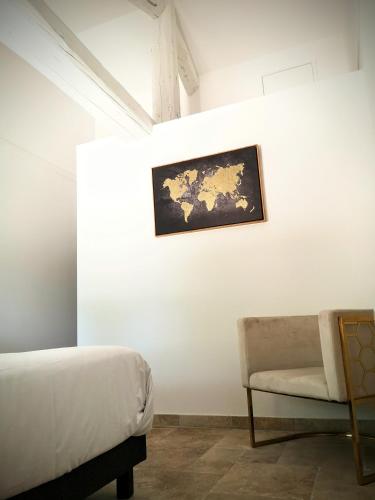 a bedroom with a bed and a chair and a painting at L'hôtel du Couvent in Vagnas