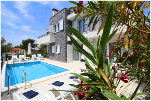 a villa with a swimming pool and a house at Apartments Nika in Primošten