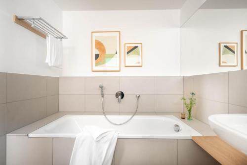 ein weißes Badezimmer mit einer Badewanne und einem Waschbecken in der Unterkunft BodenseeApartment Suite in Friedrichshafen