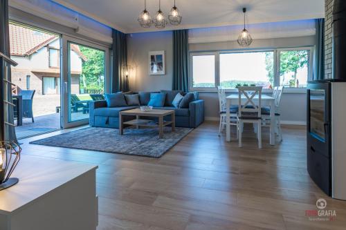 a living room with a blue couch and a table at Rydzewo domek w zabudowie szeregowej nad jeziorem in Rydzewo