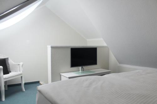 a bedroom with a bed and a tv and a chair at Hotel-Pension Am Fuchsberg in Bad Doberan