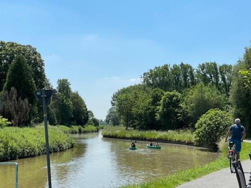 a man riding a bike next to a river with boats at Air B&B Casa Dodo in Geraardsbergen