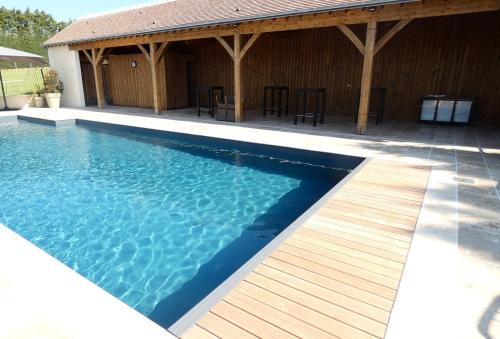 - une piscine avec une terrasse en bois à côté d'un bâtiment dans l'établissement Chez Caro, à Sennevières