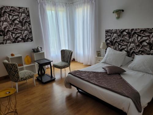 a bedroom with a large bed and two chairs at La Marviniere in Saint-Bonnet-sur-Gironde